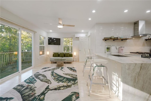 interior space with a wall mounted AC, ceiling fan, sink, and plenty of natural light