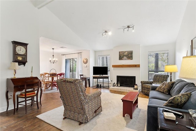 living room featuring wood-type flooring, high vaulted ceiling, an inviting chandelier, and a healthy amount of sunlight