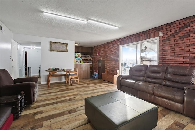 living room with hardwood / wood-style flooring, a textured ceiling, and brick wall