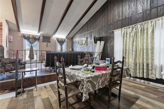 dining space with hardwood / wood-style floors, wooden walls, and vaulted ceiling