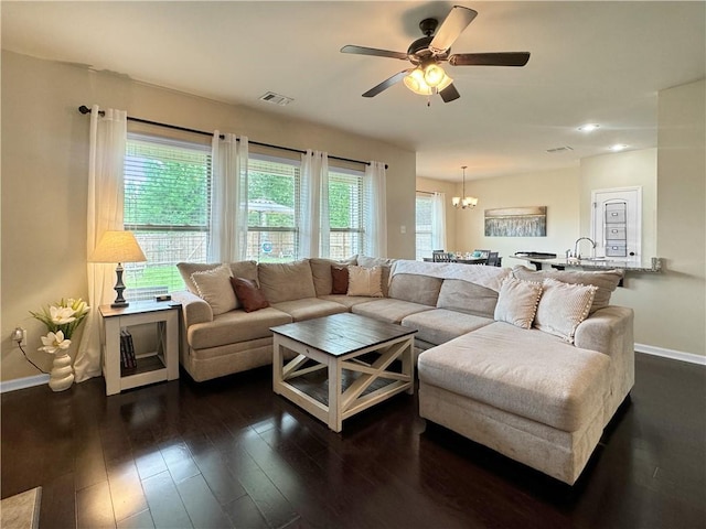 living room featuring ceiling fan with notable chandelier and dark hardwood / wood-style flooring