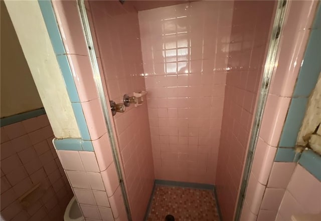 bathroom with an enclosed shower and tile walls