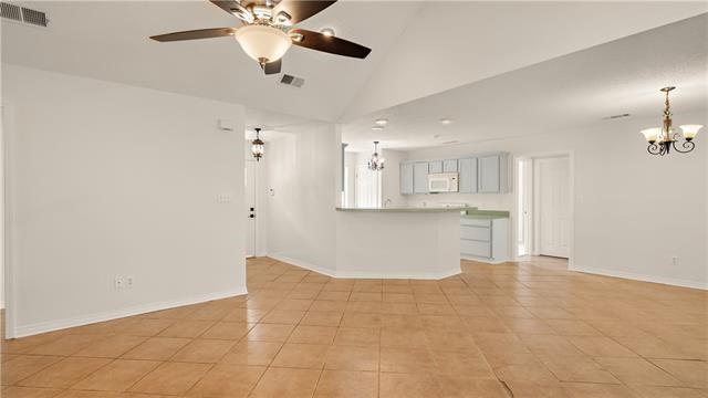 70081 9th St, Covington, LA 70433 - unfurnished living room with a chandelier, lofted ceiling, a ceiling fan, light tile patterned flooring, and baseboards