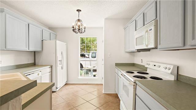 70081 9th St, Covington, LA 70433 - kitchen with white appliances, a chandelier, light tile patterned floors, pendant lighting, and a textured ceiling