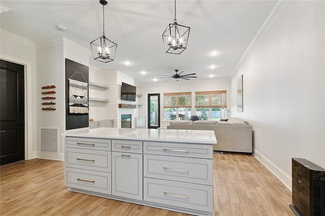 kitchen with pendant lighting, a center island, crown molding, ceiling fan, and light wood-type flooring