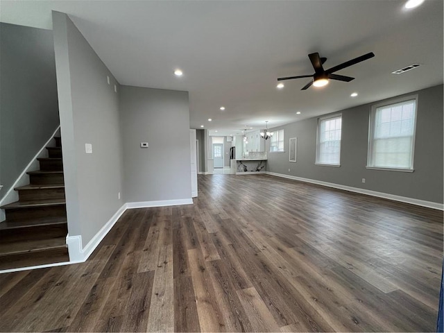 unfurnished living room with dark hardwood / wood-style floors and ceiling fan with notable chandelier