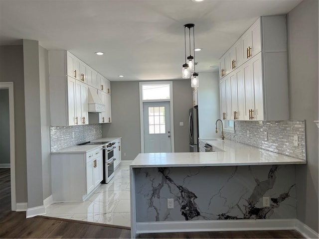 kitchen featuring sink, stainless steel appliances, premium range hood, pendant lighting, and white cabinets