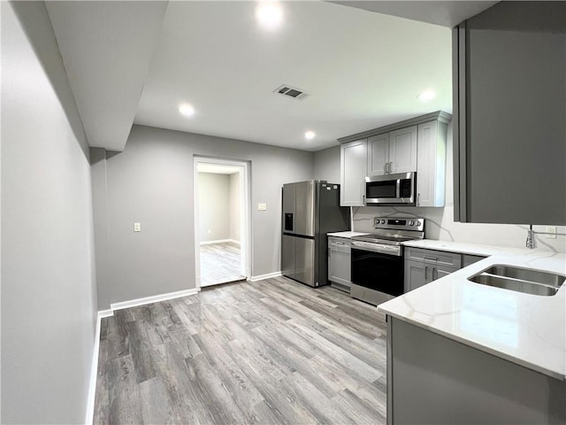 kitchen featuring gray cabinetry, sink, stainless steel appliances, and light hardwood / wood-style floors