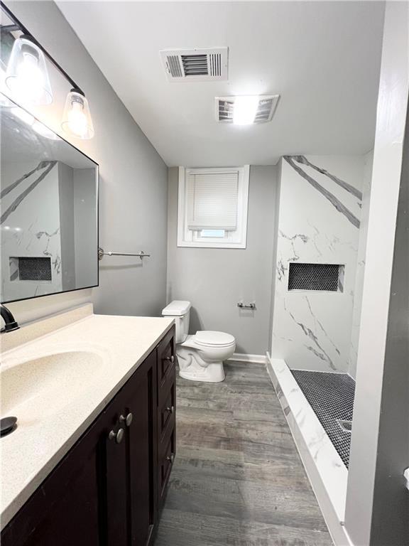 bathroom with vanity, toilet, a shower, and wood-type flooring