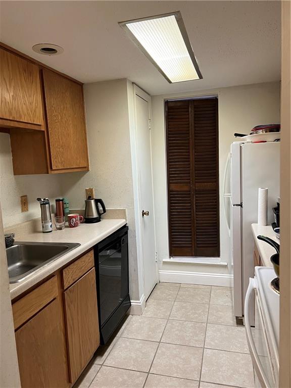 kitchen with sink, black dishwasher, white fridge, light tile patterned flooring, and range