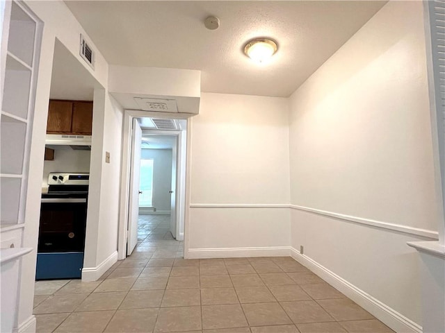empty room with light tile patterned flooring, baseboards, and a smoke detector