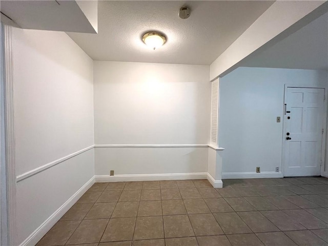 tiled spare room with a textured ceiling and baseboards