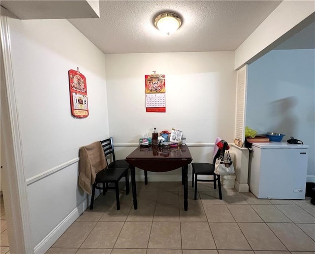 dining area featuring light tile patterned floors and a textured ceiling