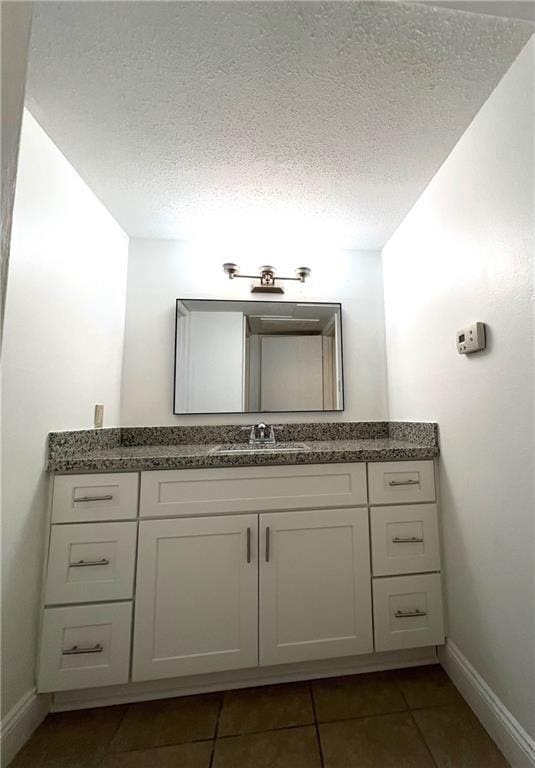 bathroom featuring tile patterned flooring, baseboards, a textured ceiling, and vanity