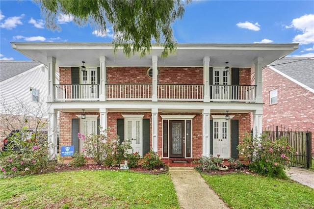 view of front of house with a porch, a balcony, and a front lawn