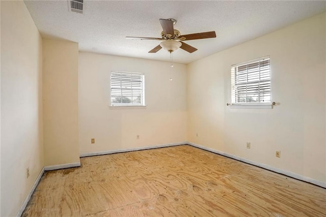 unfurnished room with a textured ceiling, a wealth of natural light, and light hardwood / wood-style flooring