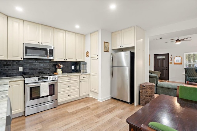 kitchen featuring light wood-type flooring, backsplash, stainless steel appliances, ceiling fan, and white cabinets