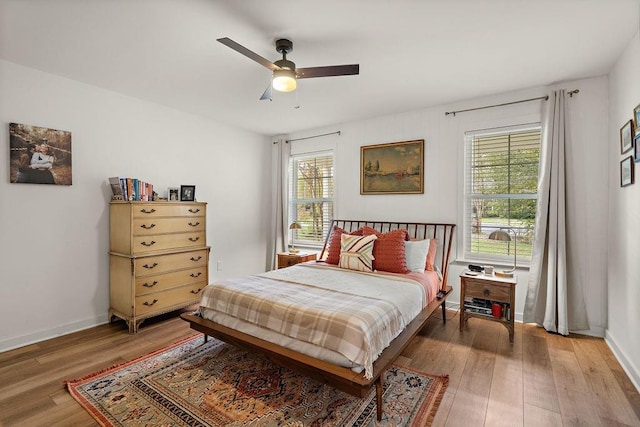 bedroom featuring hardwood / wood-style floors, ceiling fan, and multiple windows