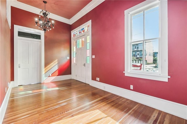 foyer entrance with a wealth of natural light, hardwood / wood-style floors, and crown molding