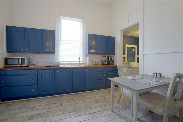 kitchen with blue cabinets, sink, butcher block countertops, and backsplash