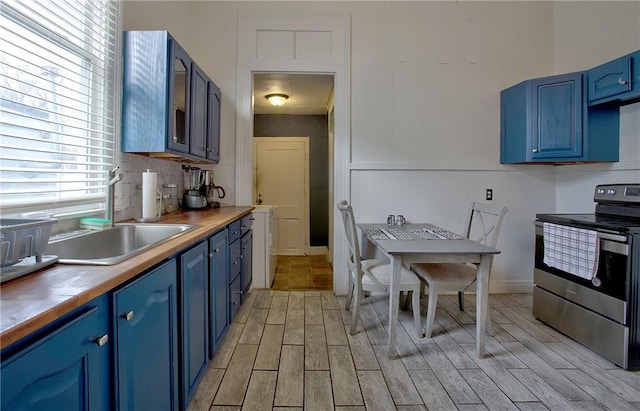 kitchen featuring wood counters, stainless steel electric range, blue cabinetry, and decorative backsplash