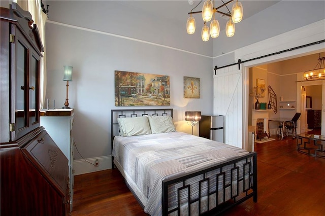 bedroom featuring a barn door, fridge, an inviting chandelier, and dark hardwood / wood-style flooring