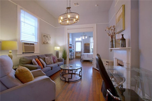 312931 N Claiborne Ave, New Orleans, LA 70117 - living room featuring cooling unit, visible vents, an inviting chandelier, a fireplace, and wood-type flooring