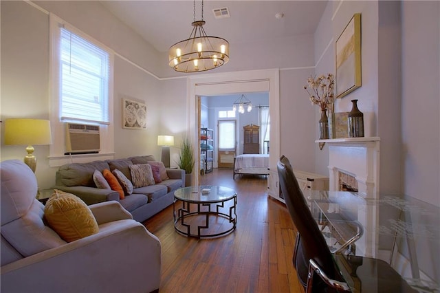 living room with dark wood-type flooring, cooling unit, and a notable chandelier