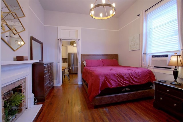 bedroom featuring stainless steel refrigerator, dark hardwood / wood-style floors, cooling unit, and a notable chandelier