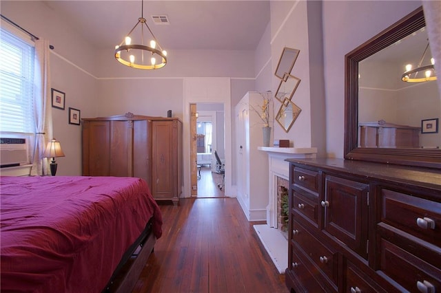 bedroom featuring dark hardwood / wood-style floors, cooling unit, and an inviting chandelier