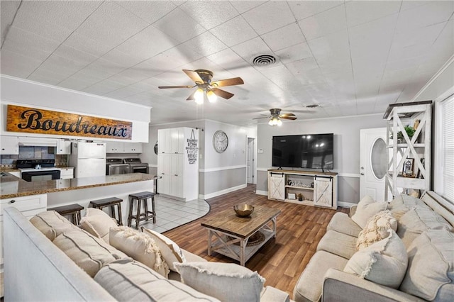 living room with ceiling fan, light hardwood / wood-style flooring, and crown molding