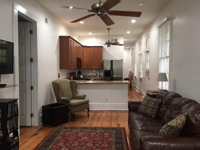 living room featuring ceiling fan, light hardwood / wood-style flooring, and sink