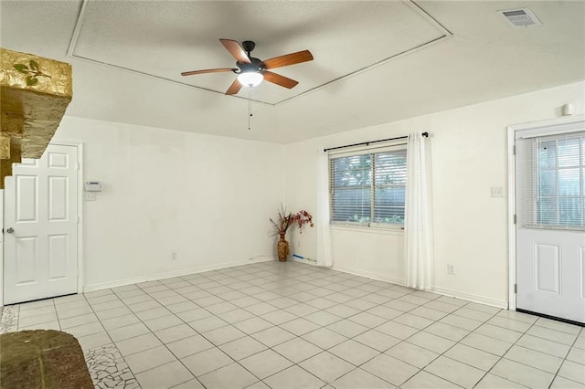 empty room with plenty of natural light, ceiling fan, and light tile patterned flooring