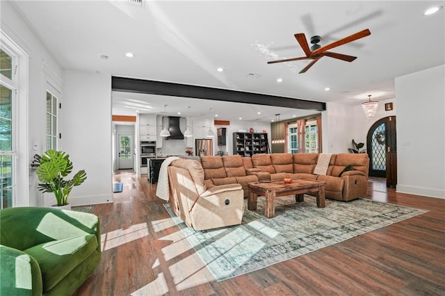 living room featuring wood-type flooring, ceiling fan with notable chandelier, and a wealth of natural light