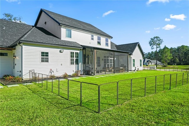 rear view of house featuring a sunroom and a lawn