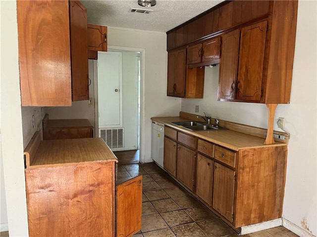 kitchen featuring dishwasher, light tile patterned floors, a textured ceiling, and sink