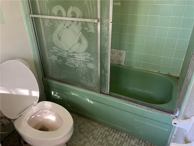 bathroom featuring shower / bath combination with glass door, tile patterned floors, and toilet