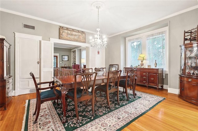 dining area featuring hardwood / wood-style floors, ornamental molding, and an inviting chandelier