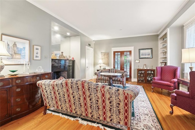 living room featuring a fireplace, plenty of natural light, built in shelves, and light wood-type flooring