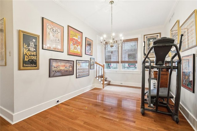 exercise area with hardwood / wood-style floors, crown molding, and a notable chandelier