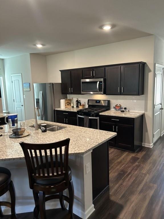 kitchen featuring appliances with stainless steel finishes, dark hardwood / wood-style flooring, a breakfast bar area, and sink