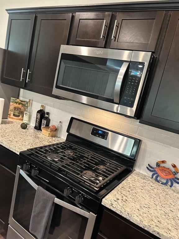 kitchen featuring light stone countertops, appliances with stainless steel finishes, backsplash, and dark brown cabinets