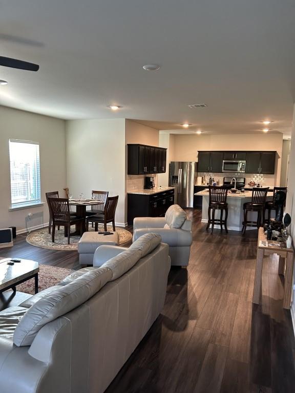 living room featuring ceiling fan and dark wood-type flooring