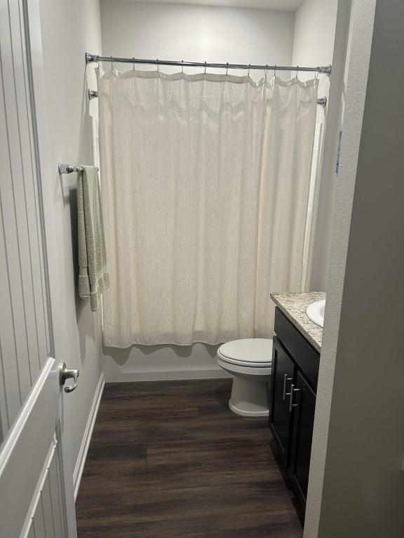 full bathroom with wood-type flooring, vanity, shower / tub combo, and toilet