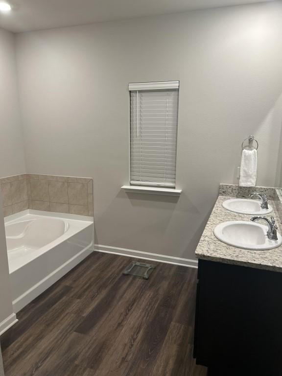 bathroom with a tub, vanity, and wood-type flooring