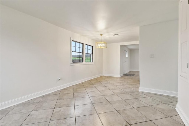 tiled empty room featuring a notable chandelier