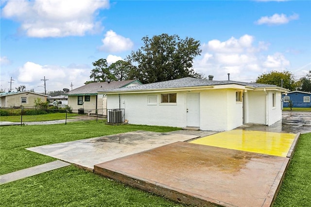 rear view of property featuring central air condition unit, a patio area, and a lawn