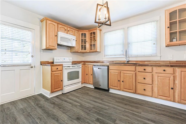 kitchen with white appliances, sink, hanging light fixtures, dark hardwood / wood-style floors, and a notable chandelier