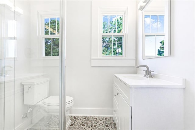 bathroom with tile patterned floors, vanity, toilet, and a wealth of natural light