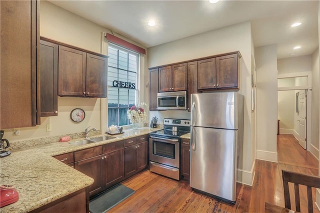 kitchen with dark hardwood / wood-style floors, sink, light stone countertops, and stainless steel appliances